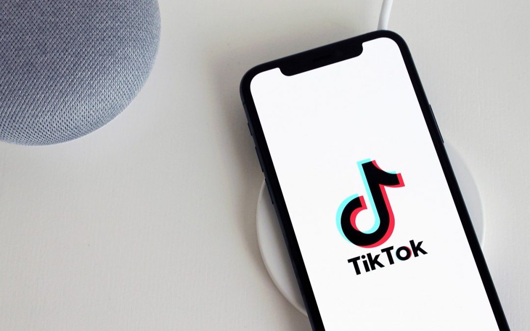 Publier du contenu sur Tiktok peut se faire directement via votre téléphone. éléphone portable type smartphone posé sur une table. Le téléphone est allumé et on peut y voir l'application TikTok.